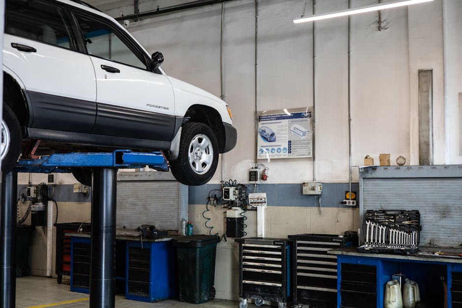 A car is elevated on a lift in a modern automotive repair shop, showcasing tools and equipment.